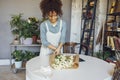 Young florist in apron creating beautiful simple daisy bouquet in craft paper