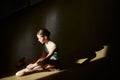 Tender teen girl, classical ballet dancer getting ready to train in ballet school on a daytime with sunlight. Putting on