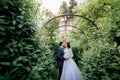 Tender wedding couple is kissing in the middle of green growing bushes in the garden