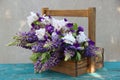 Tender white irises with purple lupins in a wooden crate. Beautiful exquisite bouquet on the green wooden table