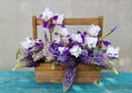 Tender white irises with purple lupins in a wooden crate. Beautiful exquisite bouquet on the green wooden table