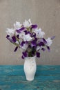 Tender white and purple irises in the white vase. Beautiful exquisite bouquet on the green wooden table