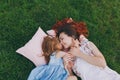 Tender woman and little cute child baby girl lie on pillows on grass in park hug, embrace and rest, have fun. Mother Royalty Free Stock Photo