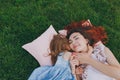 Tender woman and little cute child baby girl lie on pillows on grass in park hug, embrace and rest, have fun. Mother Royalty Free Stock Photo