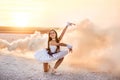 Tender young ballerina dancer in a snow-white tutu dress and white pointe shoes in pink smoke.  on a salty dried lake. Fantastic l Royalty Free Stock Photo