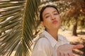 Tender young caucasian girl sends air kiss to camera walking in tropical garden. Royalty Free Stock Photo