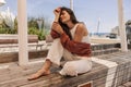 Tender young caucasian girl sits on wooden bench, posing with closed eyes outdoor. Royalty Free Stock Photo