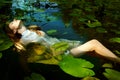 Tender young woman swimming in the pond among water lilies