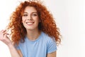 Tenderness, beauty, haircare concept. Alluring sensual young woman with natural curly red hair, rolling strand on finger