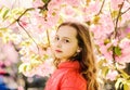 Tenderness concept. Cute child enjoy nature on spring day. Girl on dreamy face standing in front of sakura flowers