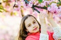 Tenderness concept. Girl on dreamy face standing in front of sakura flowers, defocused. Cute child enjoy nature on