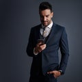 Tending to business with smart tech. Studio shot of a stylish young businessman using a mobile phone against a gray