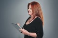 Tending to personal and business matters all on one device. Studio shot of a mature businesswoman using a digital tablet