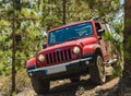 Tenerife, Spain - September 02, 2016: Jeep on a narrow rocky mountain forest road blocked by a fallen old dry pine tree. The