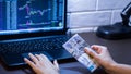 Tenge in Kazakhstan against the background of a laptop with an open chart of the currency market or stock exchange. Hands holding