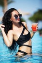 Tenned beautiful woman in black bikini and sunlasses sitting in Royalty Free Stock Photo