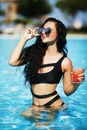 Tenned beautiful woman in orange bikini and sunlasses sitting in Royalty Free Stock Photo