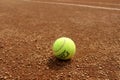 Tennis ball on a tennis clay court. Red clay tennis court. Sand on a tennis court. Close up of tennis ball on clay court