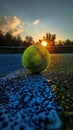 Tennis ball on a clay court at sunset