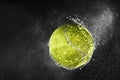 Tennis ball flying in water drops and splashes isolated on black background Royalty Free Stock Photo