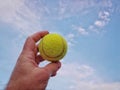 Tennis ball in hand against blue sky Royalty Free Stock Photo