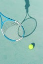 Tennis ball and racket on blue hard tennis court. Shadow of a hand holding tennis racket on the tennis court. Side view, copy Royalty Free Stock Photo