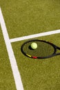 Tennis ball on tennis racket lying on sunny outdoor grass tennis court, with copy space Royalty Free Stock Photo