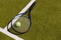 Tennis ball on tennis racket lying on sunny outdoor grass tennis court, with copy space Royalty Free Stock Photo