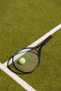 Tennis ball and tennis racket lying on sunny outdoor grass tennis court, with copy space Royalty Free Stock Photo