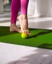 Tennis ball roll massage for feet. Woman practicing foot self-massage with a tennis ball. Physiotherapy, reflexology. Tension