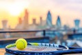 Tennis composition with yellow tennis ball on racket against blurred sunset cityscape background Royalty Free Stock Photo