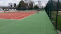 Tennis court empty red and green with net and wire fence grille Royalty Free Stock Photo