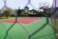 Tennis courts red green private through wire mesh fence Royalty Free Stock Photo