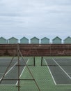Tennis courts, with row of green beach huts behind, on the sea front in Hove, Sussex, UK Royalty Free Stock Photo