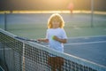 Tennis kids. Cute little child boy with tennis racket and ball on court.