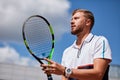 Young man in sportwear is playing tennis on out door court.