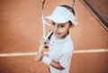 Tennis is my favorite game! Portrait of a pretty sporty child with a tennis racket. Little girl smiling at camera on tennis court Royalty Free Stock Photo