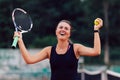 Happy girl raised her racket and ball after winning in tennis tournament