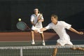 Tennis Player Hitting Ball With Doubles Partner Standing In Background Royalty Free Stock Photo