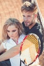 Tennis players rest on court. Couple relax on tennis court after training. Sportsman and sportswoman sit at net. Sport