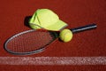 Tennis racket, peaked cap and balls on court Royalty Free Stock Photo