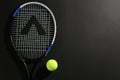 Tennis racket and ball on black background, flat lay. Space for text Royalty Free Stock Photo