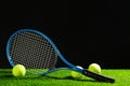Tennis racket and balls on green grass against dark background. Space for text Royalty Free Stock Photo
