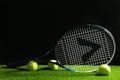 Tennis racket and balls on green grass against dark background. Sports equipment Royalty Free Stock Photo