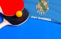 Tennis rackets and ball with flag Oklahoma on blue background, flag mockup. Table tennis competition concept