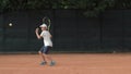 Tennis sportsmanship, ambitious child boy concentrating and focusing on game and racket beats ball on red court