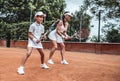 Tennis training. Cheerful mother in sports clothing teaching his daughter to play tennis while both standing on tennis court Royalty Free Stock Photo