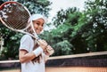 Tennis training for young kid outdoors. Portrait of happy sporty little girl on tennis court. Caucasian child in white tennis Royalty Free Stock Photo