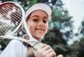 Tennis training for young kid outdoors. Portrait of happy sporty little girl on tennis court. Caucasian child in white tennis Royalty Free Stock Photo