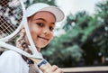 Tennis training for young kid outdoors. Portrait of happy sporty little girl on tennis court. Caucasian child in white tennis Royalty Free Stock Photo